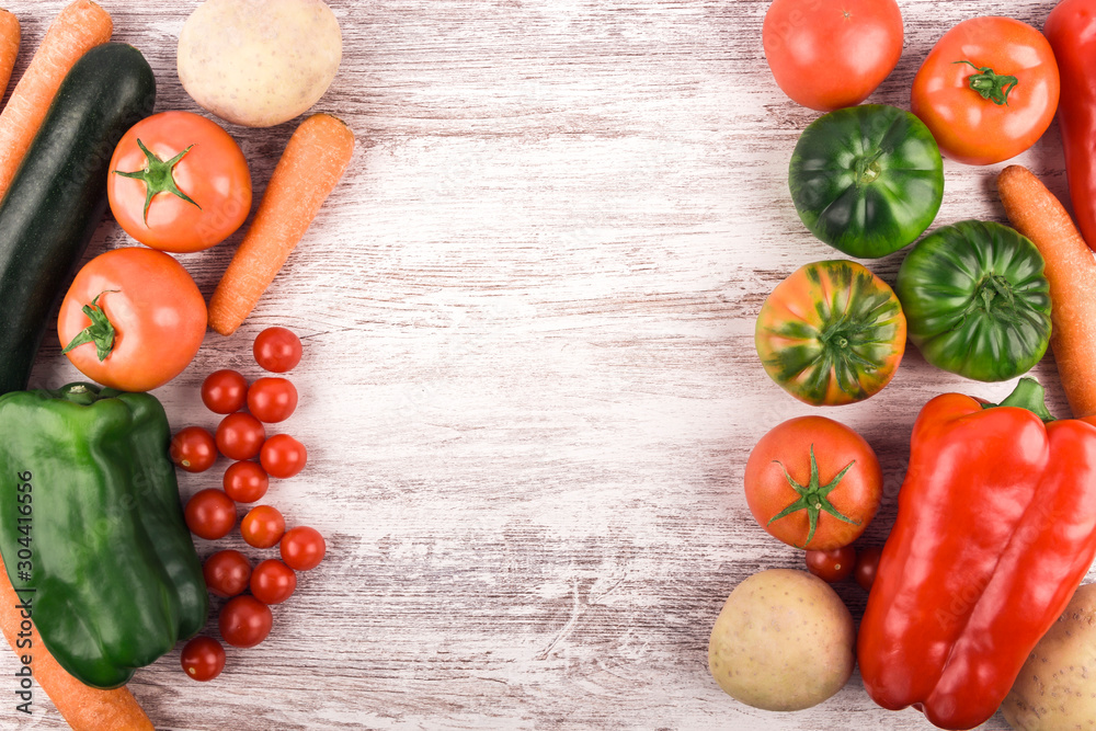 Top view of delicious fresh and healthy raw vegetables placed to leave a space for text or an image. Rustic white wood background. Copy space. Healthy food. Natural products. Nature and well-being Top view of delicious fresh and healthy raw vegetables placed to leave a space for text or an image. Rustic white wood background. Copy space. Healthy food. Natural products. Nature and well-being