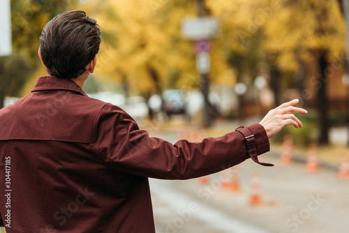 Back view of man catching taxi on street