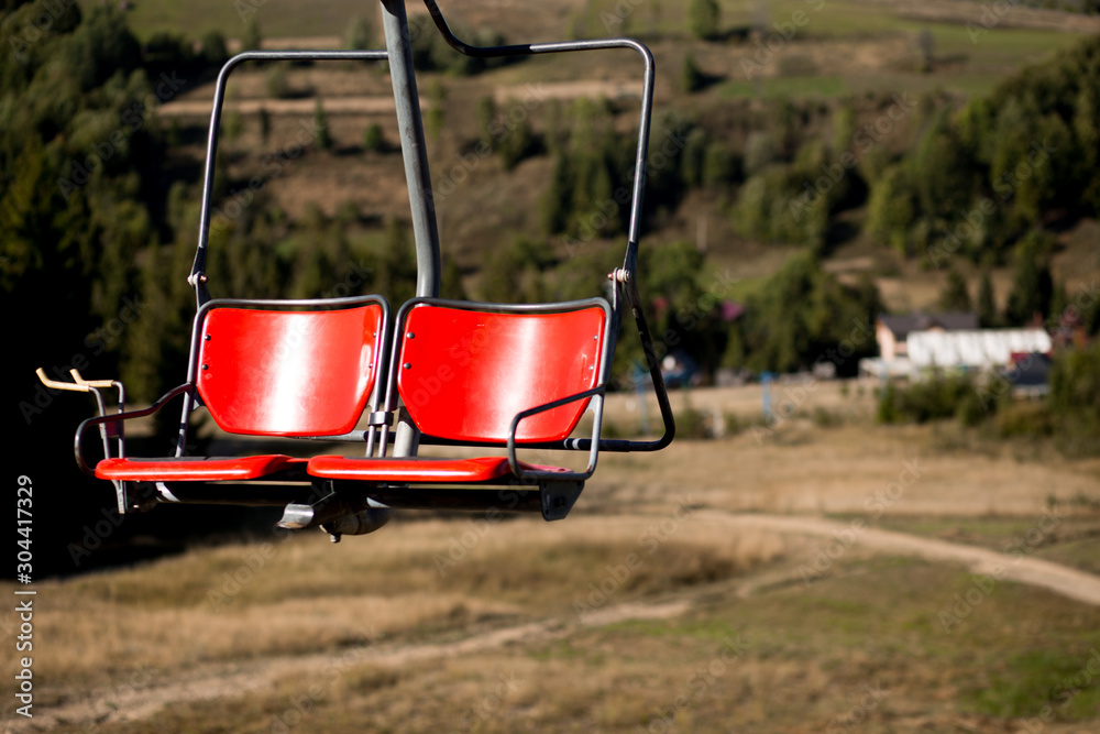 Close up of red chairlift going over trees in summer on Mountain. Carpathian national park Close up of red chairlift going over trees in summer on Mountain. Carpathian national park