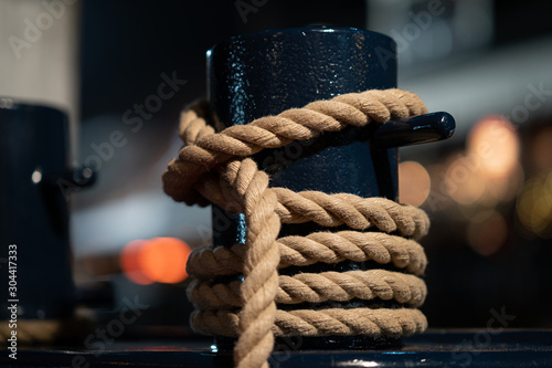 Mooring bollard intertwined with mooring rope at the port.