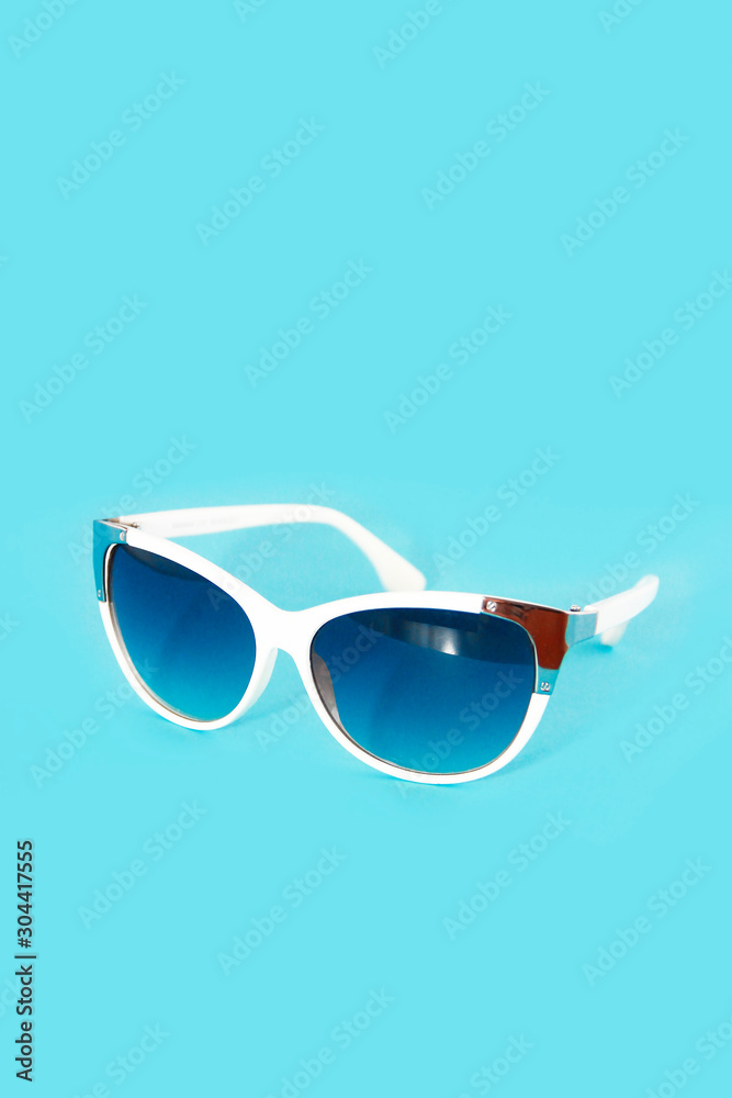 sunglasses in a white plastic frame and blue glasses lenses on a blue background sunglasses in a white plastic frame and blue glasses lenses on a blue background