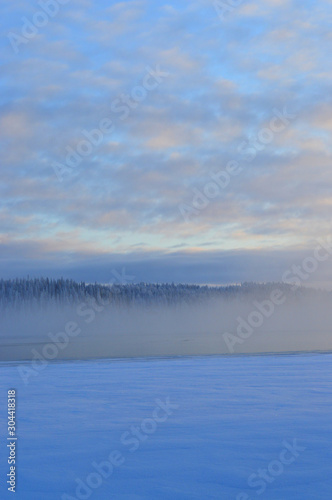 Finnisht winter  Kuusamo  Lake Porontima.. Colorful cloudletts. Mist on the lake .