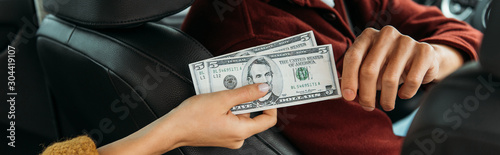 Cropped view of woman giving dollar banknotes to taxi driver, panoramic shot