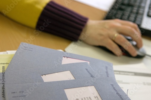 Hand with mouse and computer. Dutch tax papers. Belastingdienst. Blue enveloppe. tax assessment. Administration. Bookkeeping. Belastingformulier invullen. photo
