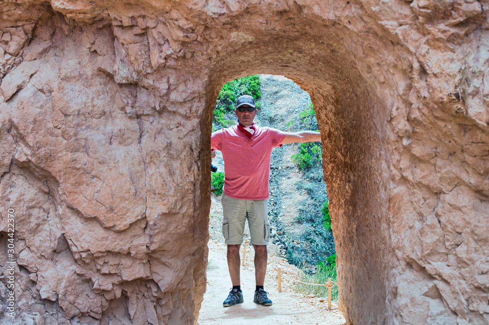 Happy man visiting national park embracing natural arch Happy man visiting national park embracing natural arch
