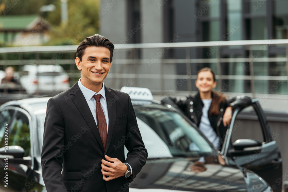 Selective focus of smiling businessman and taxi driver by car Selective focus of smiling businessman and taxi driver by car