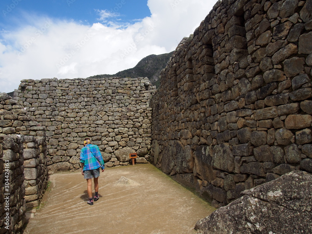 A woman tourist walking in the ancient Inca town of Machu Picchu, Ruins of Inca Empire city, Peru