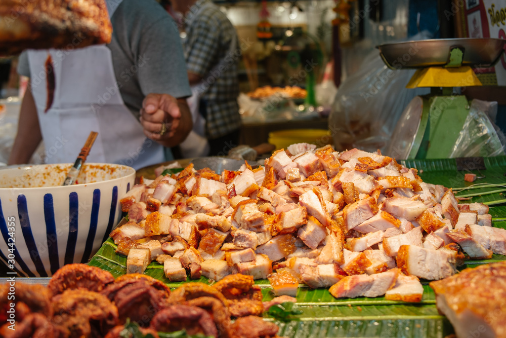 Chopped crispy pork on banana leaves for sale in a local street food shop in Bangkok, Thailand.