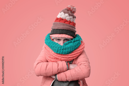 Handsome caucasian funny man in several hats and scarfs being offended or feeling cold photo