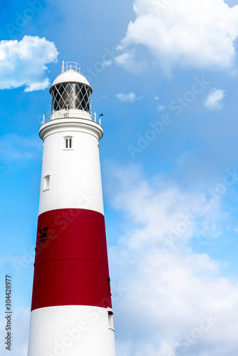 Large lighthouse on a clear blue sky day with white clouds at sunrise in England
