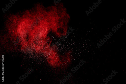 Red powder explosion on black background. Freeze motion of red dust particles splash.