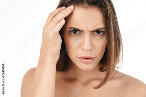 Portrait of confused young brunette half-naked woman touching her face