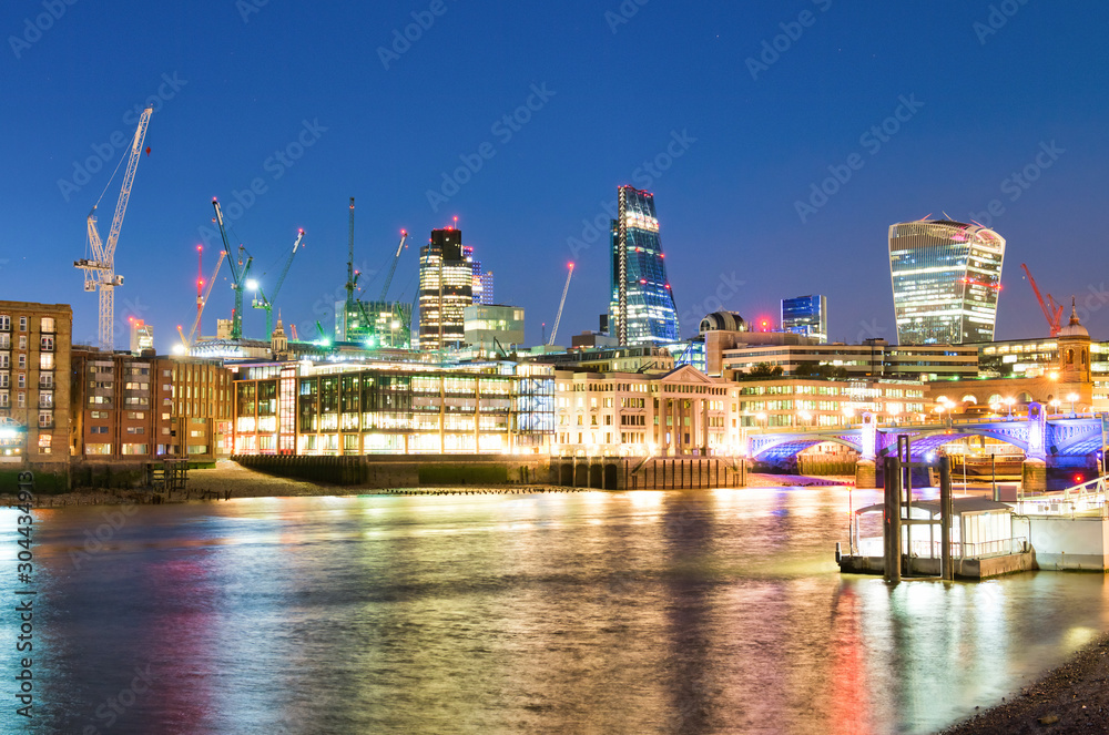 City of London night skyline with River Thames reflections, UK