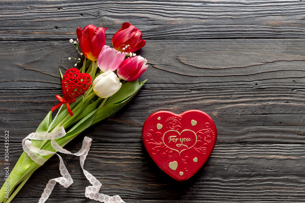 Romantic bouquet of tulips and box with candies in the shape of heart