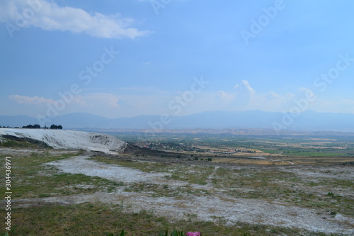 Pamukkale travertines captured with fields and some people around. Captured in daytime.