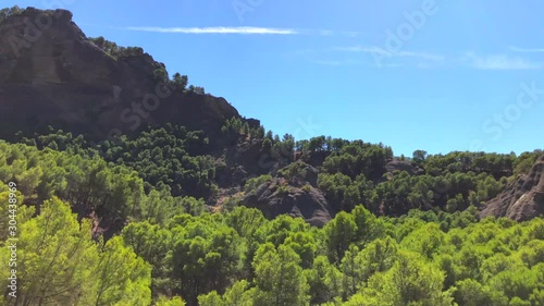 Driving through mountains and green nature park with blue sky in El Chorro near Malaga, Spain