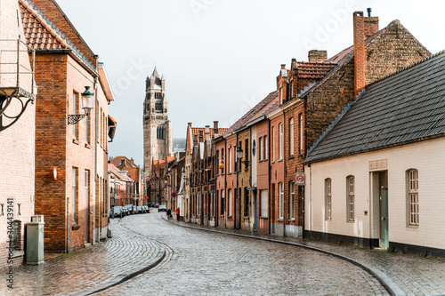 Fototapeta Starożytne uliczki starego miasta Brugge w Belgii. Pusta ulica z tartaku rozciągająca się w dal w deszczową pogodę.