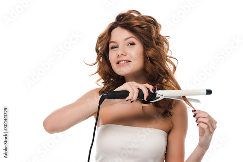 happy girl looking at camera and curling hair isolated on white