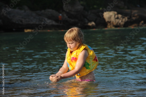 a child in a vest bathes in the sea