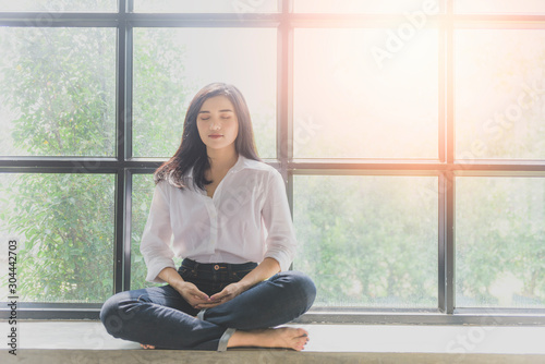 Portrait of calm Asian girl meditation in the morning. Young woman indoors Living lifestyle at home.