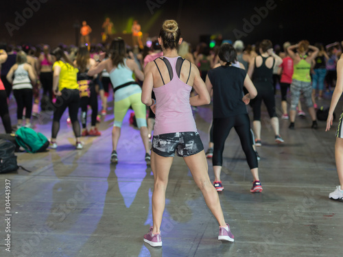 Fitness Workout in Gym: People doing Exercises in Class with Music and Teacher on Stage