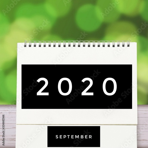 White blank paper desk spiral September calendar on wood with green abstract background. Calender of 2020 and empty month or Date to enter text and numbers.