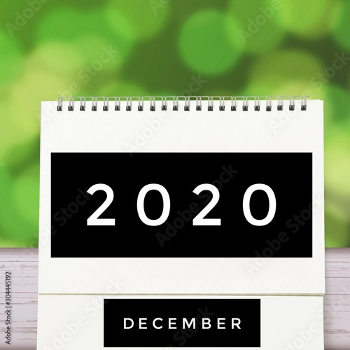 White blank paper desk spiral December calendar on wood with green abstract background. Calender of 2020 and empty month or Date to enter text and numbers.
