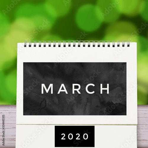 White blank paper desk spiral March calendar on wood with green abstract background. Calender of 2020 and empty month or Date to enter text and numbers.