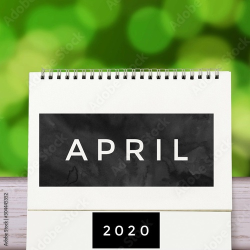 White blank paper desk spiral April calendar on wood with green abstract background. Calender of 2020 and empty month or Date to enter text and numbers.