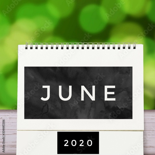 White blank paper desk spiral June calendar on wood with green abstract background. Calender of 2020 and empty month or Date to enter text and numbers.