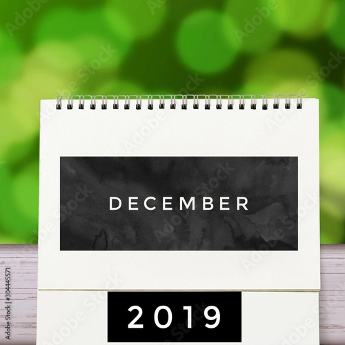 Simple 2019 December monthly calendar on table with office supplies. December month 2019 Spiral Calender with green abstract.
