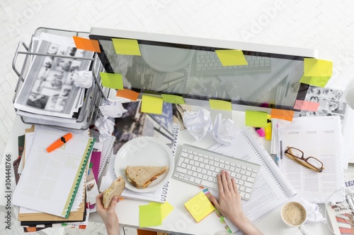 Cropped image of businesswoman having breakfast while working on computer in office