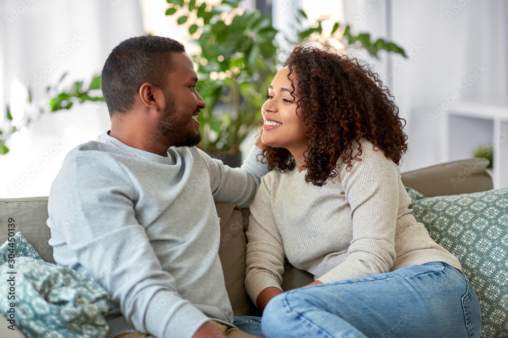 © Syda Productions - relationships, communication and people concept - happy african american couple sitting on sofa and talking at home