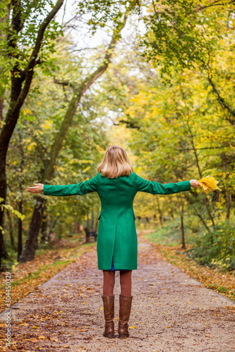 Fototapeta Naklejka Na Ścianę i Meble -  Woman with her arms outstretched holding fall leafs and enjoys in autumn.