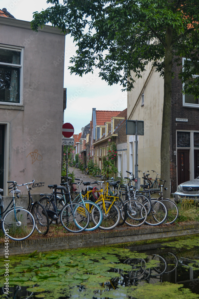 ten bicycles tied together at the edge of a canal in a Dutch town in summer