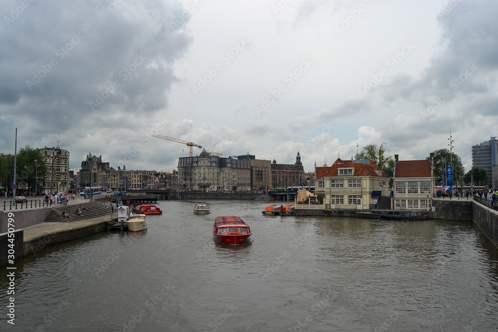 Typical Dutch cityscape with boats crossing the canals, classic buildings and a crane