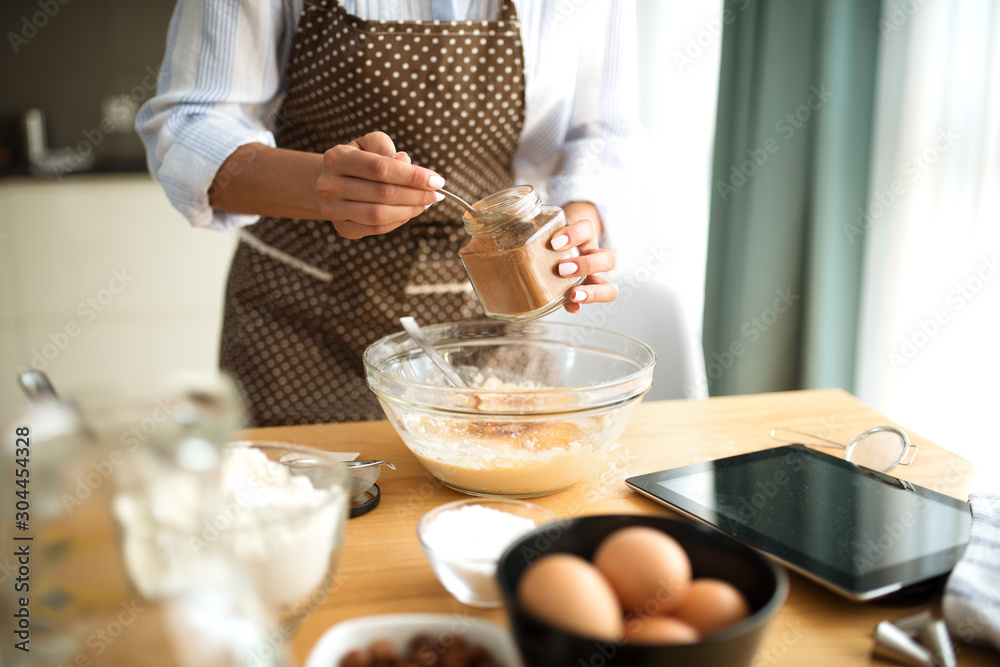 Young woman in the kitchen and inserts ingredients Young woman in the kitchen and inserts ingredients