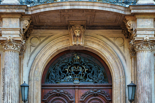 Antique entrance door with decorative elements and wrought iron and street lamps