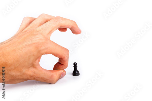 Human hand flicking a chess piece, huge hand flicks away a small tiny black pawn. Flick gesture isolated on white. Danger, anxiety and peer pressure, being fired, losing job due to layoffs concept