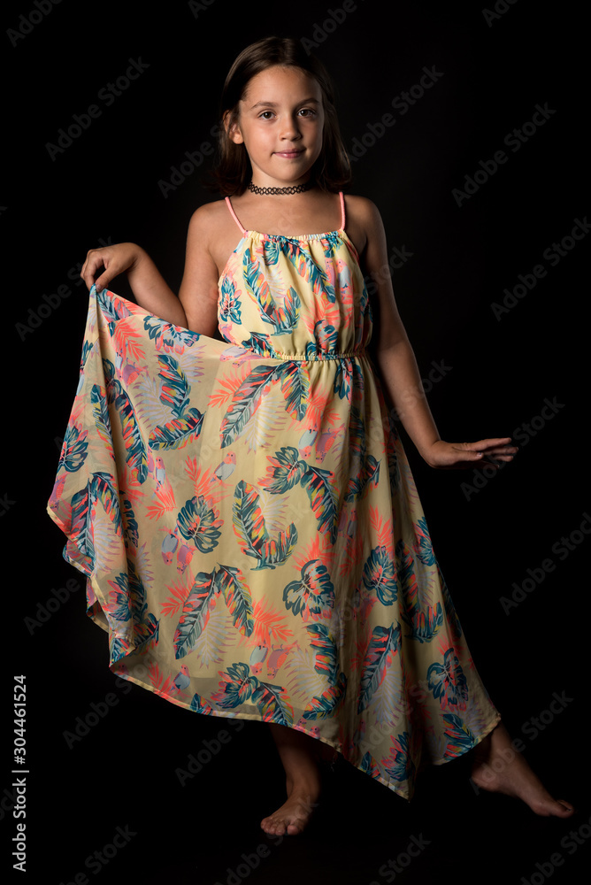 Portrait of happy young little girl holding long colourful dress.