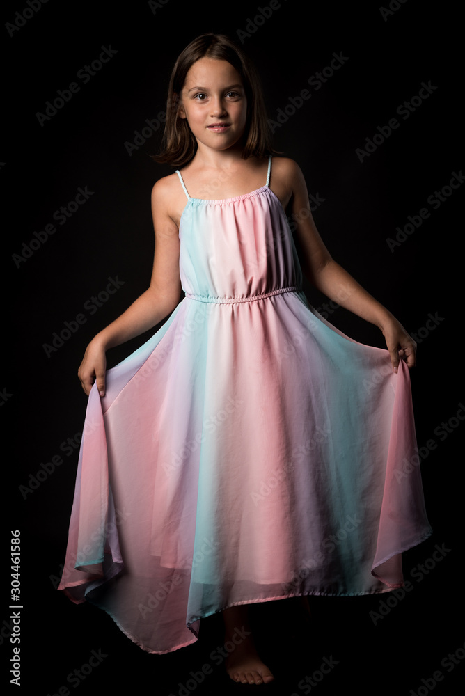 Portrait of happy young little girl holding long colourful dress.