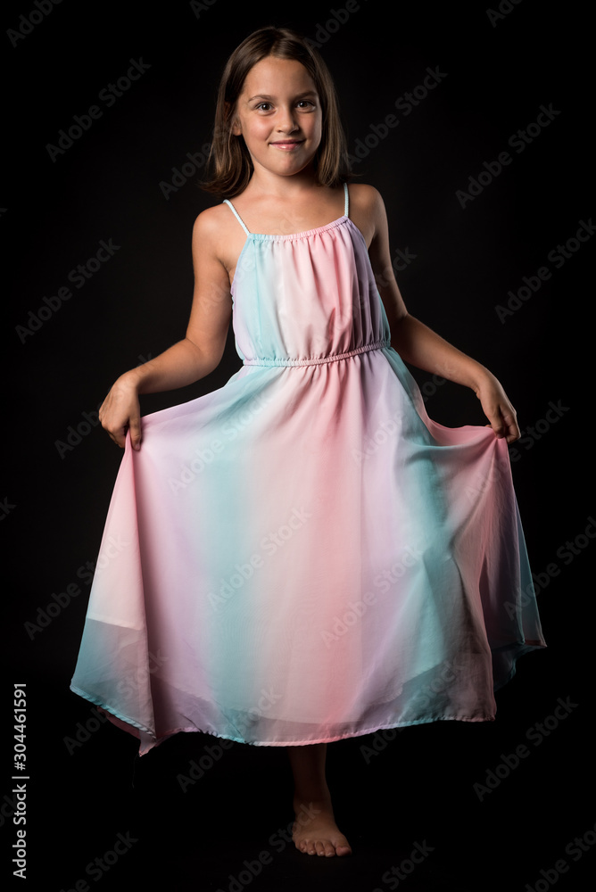 Portrait of happy young little girl holding long colourful dress.