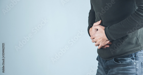 Foto man hand in ache stomache on gray background