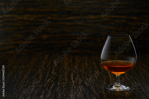 Quadro su tela Full glass of cognac on a wooden table, selective focus with copy space