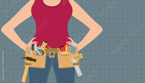 Handywoman with hands on waist and tool belt on grey peg board background, repair and DIY concept