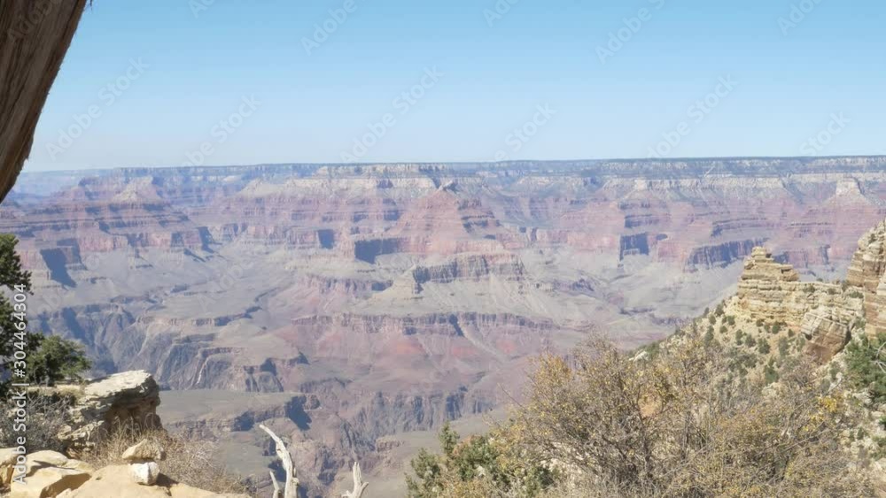 Overview Of The Grand Canyon, National Park Red Layered Rock Formations Under The Bright Blue Sky with Cliffs, Green Trees, And Grass Nearby - Wide Shot Overview Of The Grand Canyon, National Park Red Layered Rock Formations Under The Bright Blue Sky with Cliffs, Green Trees, And Grass Nearby - Wide Shot