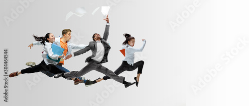 Happy office workers jumping and dancing in casual clothes or suit with folders on white. Ballet dancers. Business, start-up, working open-space, motion and action concept. Creative collage. Copyspace photo