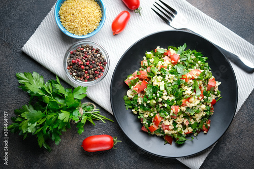 Traditional oriental salad Tabbouleh with bulgur and parsley on a dark background top view copy space.