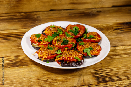 Baked eggplants with tomatoes and cheese on wooden table