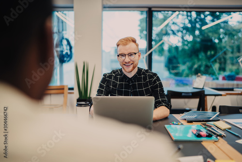 Cheerful young man with laptop in office